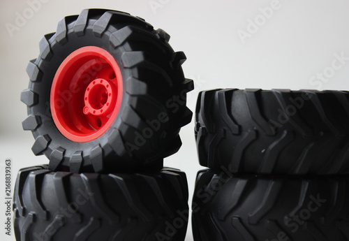 Stack of figurines of tractor wheels with red rims isolated on white