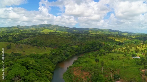A river meanders through lush, green waterways with trees and a cloudy sky. Landscape with a stream flowing through a mountain valley. Mountainous landscape of Central America, aerial view.