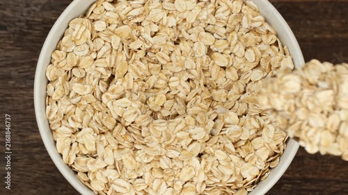 Raw oatmeal scoop with spoon from bowl. close up