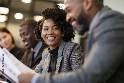 Smiling african american businesswoman looking at documents during meeting with colleagues