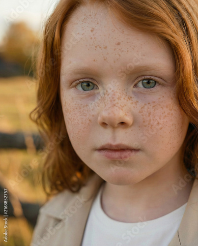 Rustic early autumn photoshoot of a little red-haired girl with a red setter dog near an old barn, warm countryside mood with soft seasonal light
