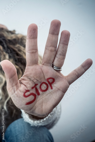 Fotografie Person holding up hand with the word STOP written in red on the palm to convey a