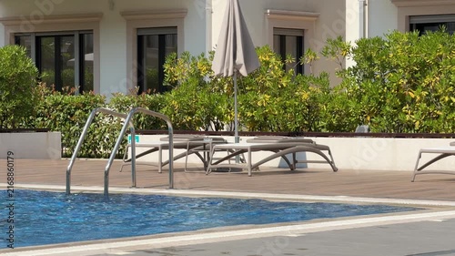 Hotel sun loungers by the swimming pool on a sunny summer day, relaxing resort atmosphere and luxury vacation concept