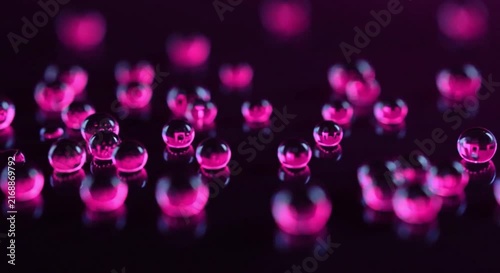 Glowing neon droplets slide across black glass in a seamless colorful futuristic macro background.