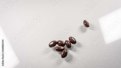 Canvastavla Close up of brown oval tablets spilled from a white medicine bottle on a clean white background