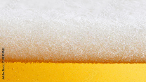 Close-up view of fresh cold beer foam and bubbles on top of golden liquid, macro shot of carbonation in a refreshing beverage for concepts