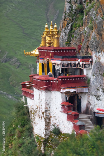 Tibetan monastery clings to a rocky cliff above a green valley