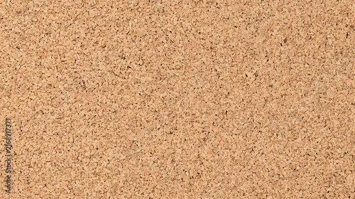 A close-up view of a textured cork surface, displaying natural variations and a warm brown hue.