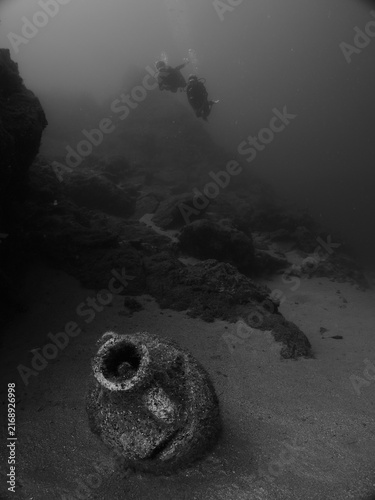scuba divers are exploring antic old amphoras underwater