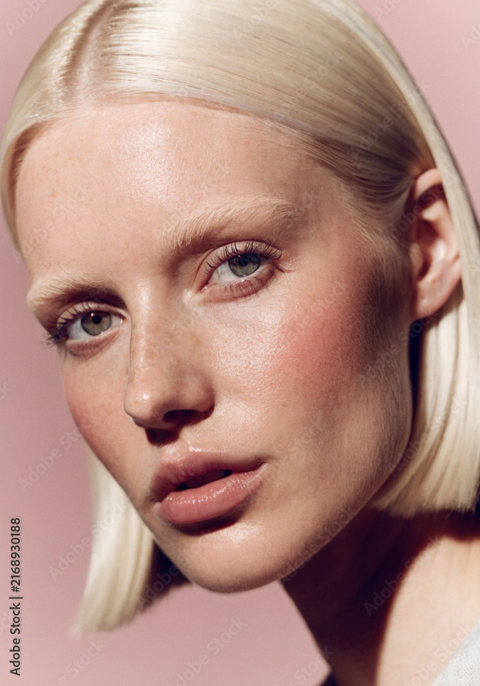 Fototapeta premium Close-Up Portrait of Caucasian Woman with Platinum Blonde Bob Against Soft Rose Background