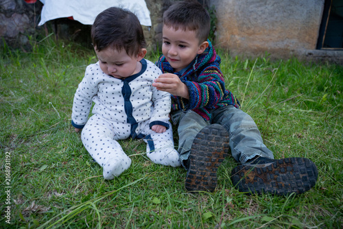 Cuadro en lienzo Two cute brothers sitting on the green grass in an outdoor garden