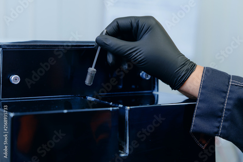 Konstfotografi Gloved hands scooping black powder magnetite iron ore into vial on lab bench, co