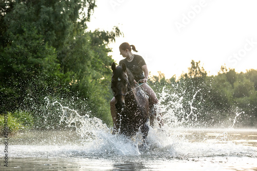 Frau badet mit Pferd im See