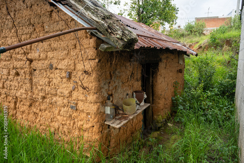 Facade of the grandparents' rustic adobe country house with a metal sheet roof.