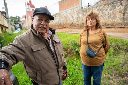Older couple enjoying a cool afternoon in their country garden with a church and cemetery in the background.
