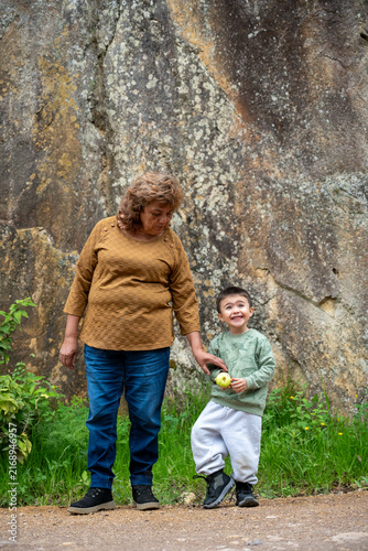 Grandmother holding her grandson's hand while walking on a dirt road in Mineral del Chico, Mexico.