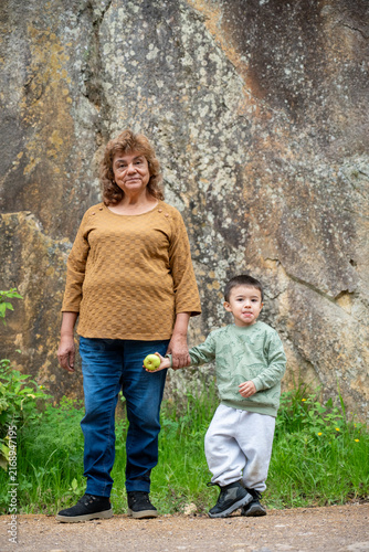 Senior woman looking proudly at her grandson by a rocky cliff during a walk.