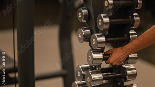 Fotografie Hand reaching for a dumbbell from a rack in a gym setting