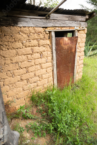 Vertical view of a rustic adobe house with a rusty metal door in rural Hidalgo, Mexico.