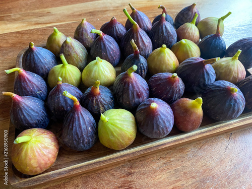 Fresh ripe purple and green figs arranged on wooden tray high angle view
