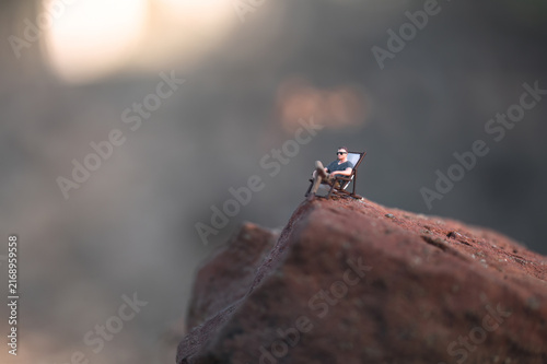 Man relaxing on top of a rock at sunset