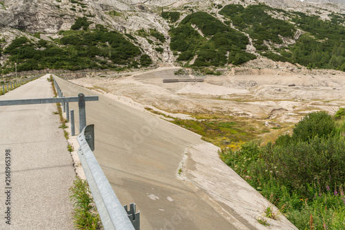 Canazei, Italy. Lago di Fedaia reservoir showing exposed lakebed and concrete dam during drought and low water levels