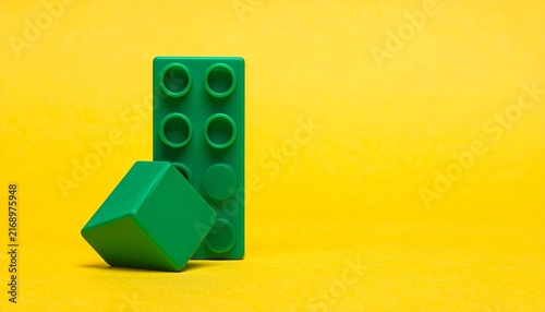 Single green plastic toy building block top view isolated on a bright yellow background
