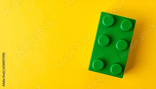 Single green plastic toy building block top view isolated on a bright yellow background