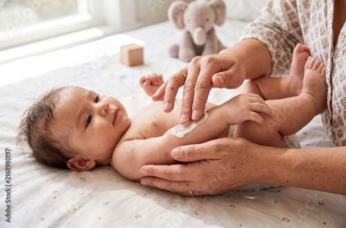 Parent applying moisturizing cream on baby arm during daily care routine