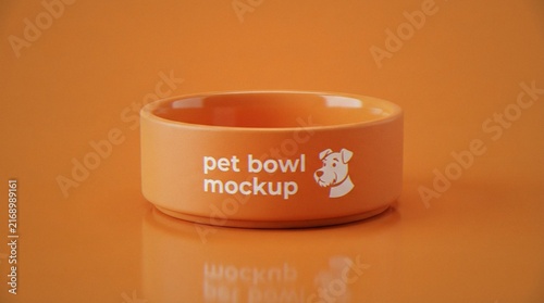 A high-quality 3D render of an orange ceramic pet bowl featuring a minimalist dog icon and custom text, set against a matching orange studio background with soft reflections.