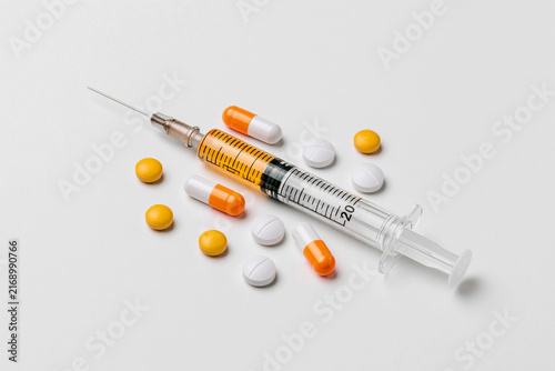 Syringe with medicine and pills arranged on a flat surface