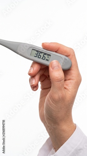 A close-up shot of a person holding a digital thermometer displaying a normal temperature of 36.6°C