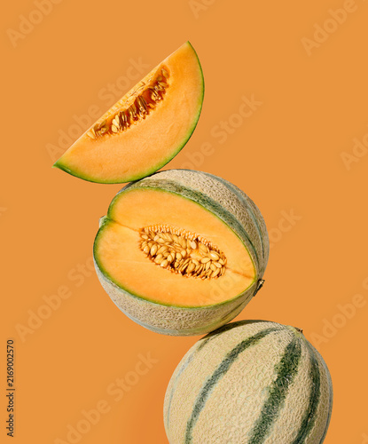Fresh ripe melon arranged with whole and sliced pieces on a light orange background
