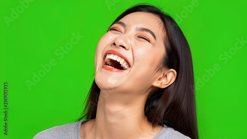 Gleeful Laughter on Green Screen: A young woman throws her head back in uninhibited laughter, her eyes squeezed shut in pure joy against a vibrant green backdrop.