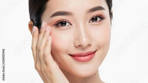 Radiant Beauty: A young Asian woman with flawless skin and a gentle smile, her hand delicately touching her cheek, embodies natural elegance and serene confidence.