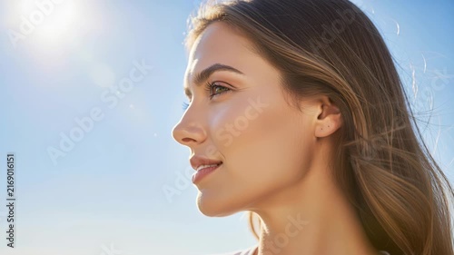 Golden Hour Radiance: A beautiful young woman with long, flowing hair basks in the warm glow of the sun, her face turned towards the sky, embodying a sense of peace and optimism.