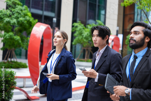 Konstfotografi Three young business professionals wearing conference badges move quickly past t