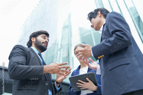 Photography Two businessmen and a businesswoman seal a partnership with a warm handshake out
