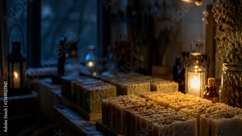 Handmade organic soap bars, rustic wooden workshop setting, warm candle lighting, natural skincare products, artisanal apothecary vibe