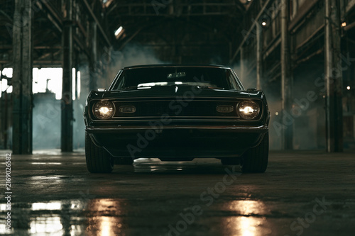 Cinematic muscle car parked in industrial warehouse