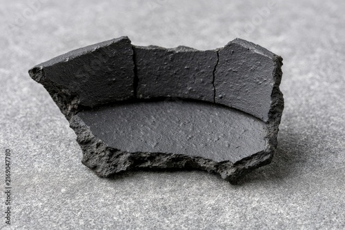Charcoal material texture, on a neutral surface with soft studio light and clean shadows