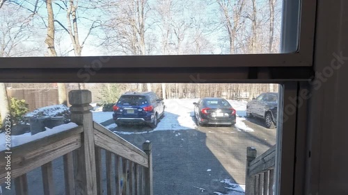 Berkeley Heights, NJ, USA - 02-15-2026: opening the door and going outside in the driveway on sunny snowy day in February