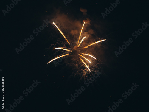 Canvastavla Golden star-shaped pyrotechnic firework bursts with thick glowing sparks and smoke clouds in the pitch-black night sky during an event