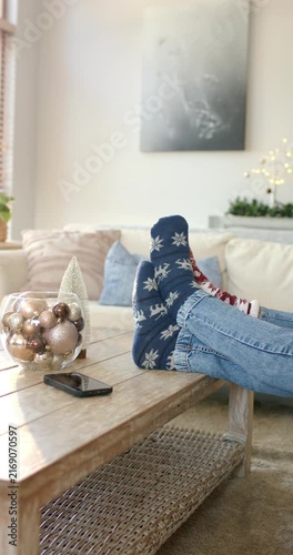Vertical video: Legs sliding onto table with bowl of ornaments while flexing socks for holiday rest