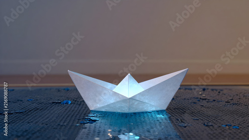 Origami paper boat on wet reflective surface