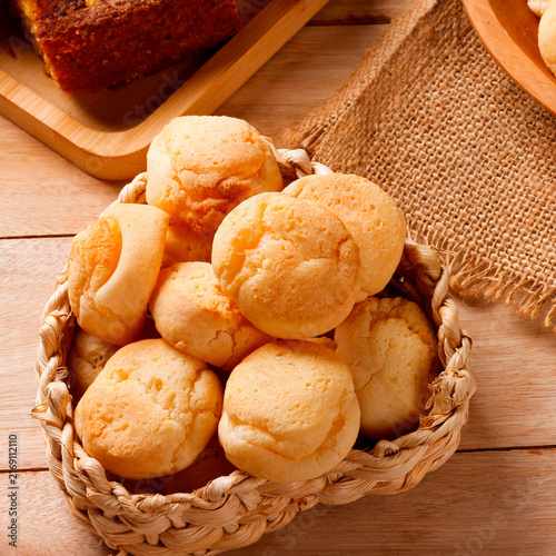 Homemade Brazilian cheese bread served on a wooden platter, accompanied by fresh Minas cheese, butter, and black coffee