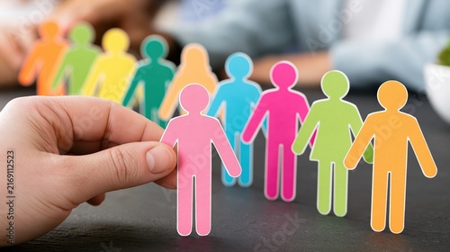 Hand selecting a single colorful person from a row of many.
