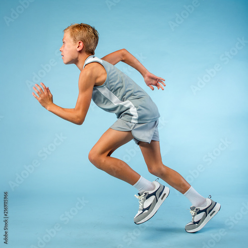 Fit young male sprinter in track team uniform running at full speed