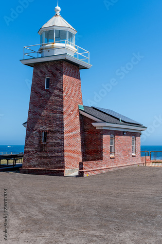 sunny vertical shot of the historic red brick Mark Abbott Memorial Lighthouse under a clear blue sky