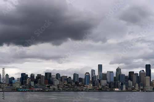 wide-angle view across Elliott Bay toward the downtown Seattle skyline under dramatic, dark storm clouds